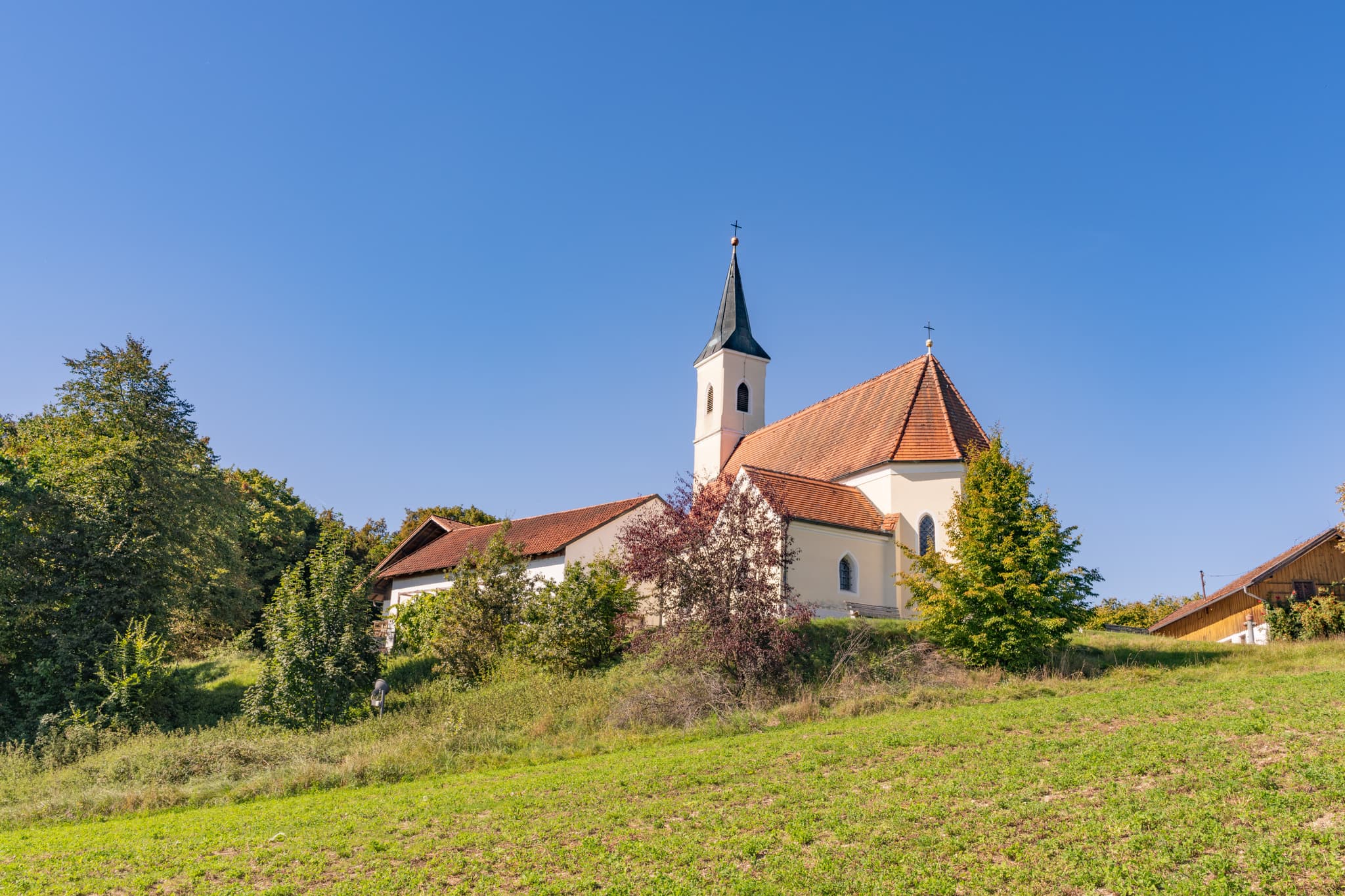 Wallfahrtskirche Mariä Himmelfahrt in Guteneck Johanniskirchen, Rottal-Inn, Niederbayern, Deutschland. Kirchturm und Dach vor blauem Himmel im Holzland.