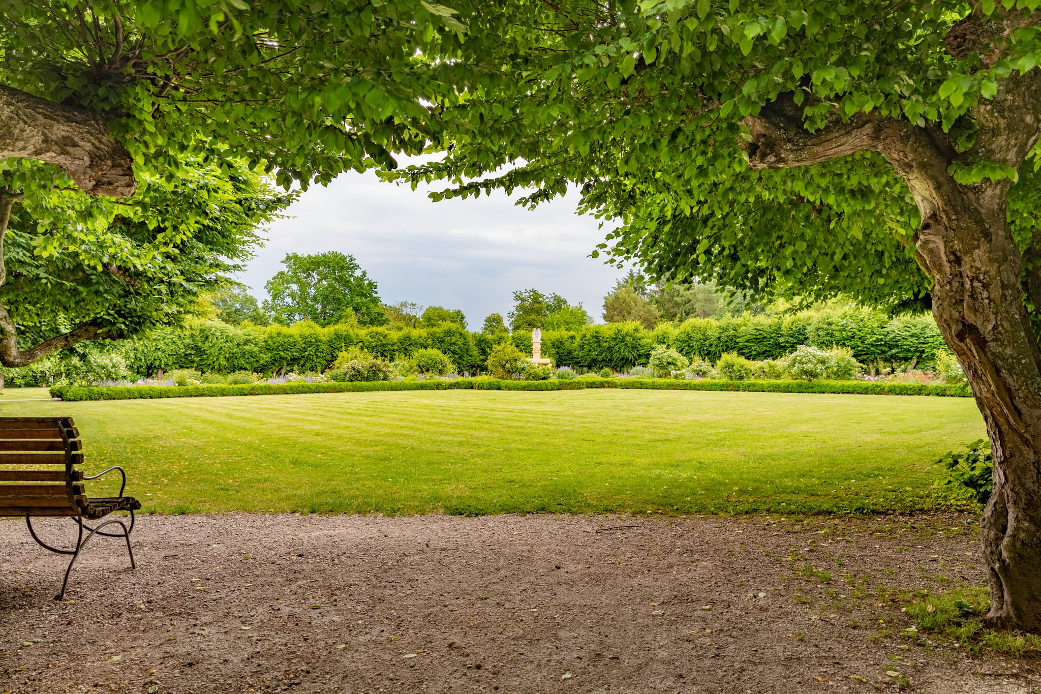 Herrengarten Park in Reichersberg, Bezirk Ried, Oberösterreich. Grünflächen, Bäume und eine Bank prägen diesen Park, Österreich.