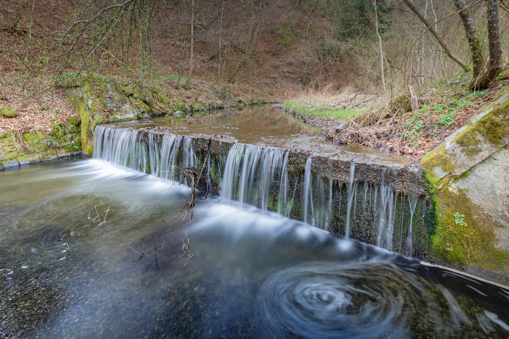 Rockersbach Wasserfall in Hochmühl, Reischach, Landkreis Altötting, Oberbayern, Deutschland. Der Bach liegt schattig im Wald.