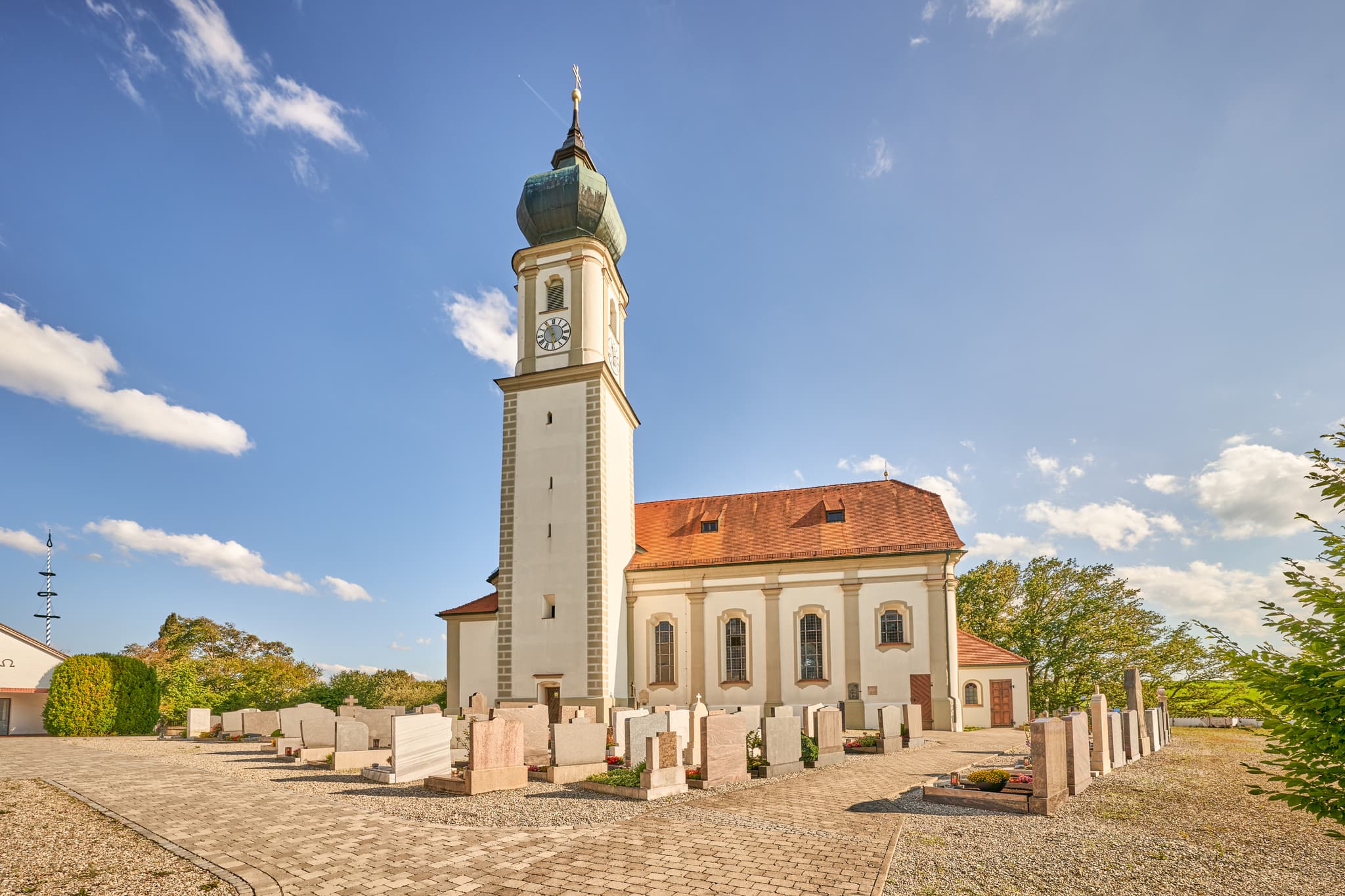 Kirche St. Martin in Niedertaufkirchen, Landkreis Mühldorf am Inn, Oberbayern. Das Gotteshaus mit Friedhof unter blauem Himmel im Inn-Salzach, Deutschland.