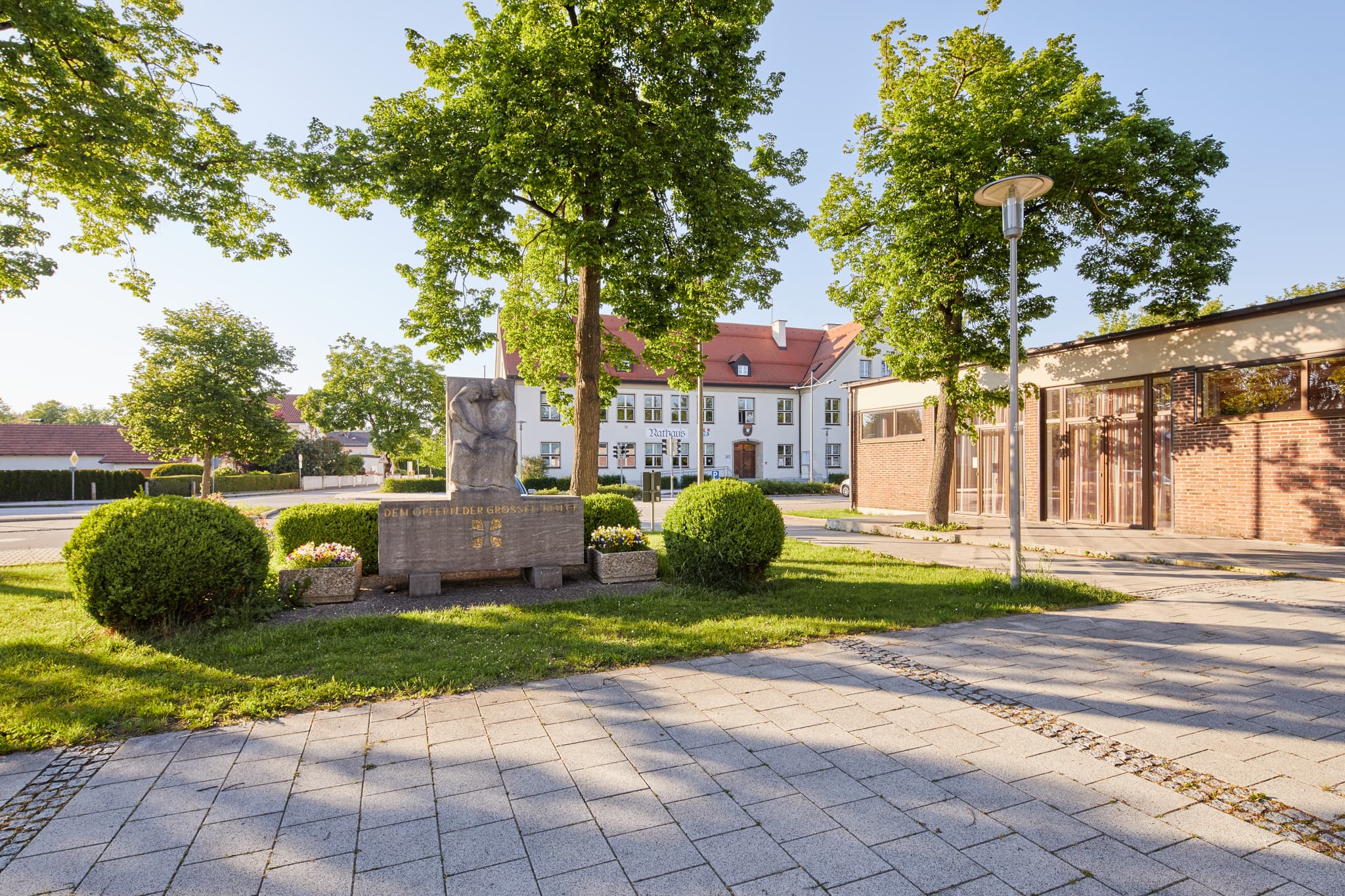 Ein Kriegerdenkmal und das Rathaus am Dorfplatz in Emmerting, Altötting, Oberbayern, Deutschland. Szenerie in der Region Inn-Salzach.
