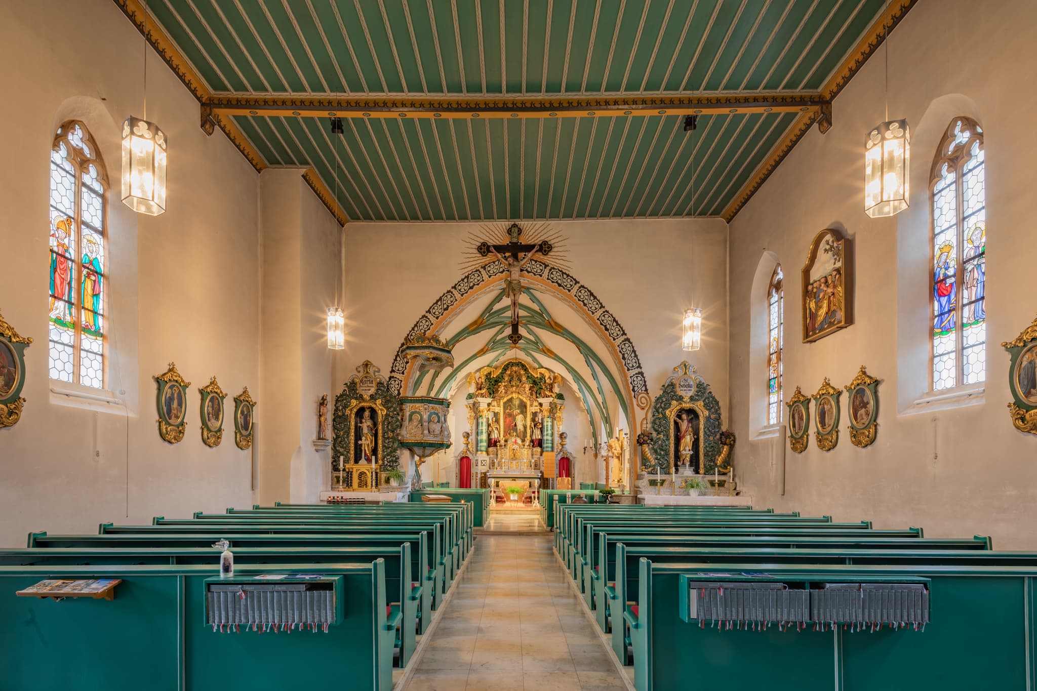 Innenansicht der Pfarrkirche St. Johannes der Täufer in Weng, Bad Griesbach, Lkr. Passau, Niederbayern, Deutschland. Grünes Gestühl, Altarraum und Decke.