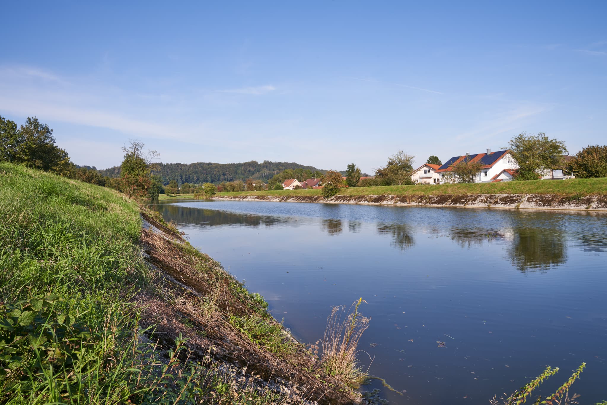 Landschaftsaufnahme der Isen mit grünen Ufern und Häusern bei Kronberg, Winhöring, Altötting. Gelegen in Oberbayern, Region Inn-Salzach, Deutschland.