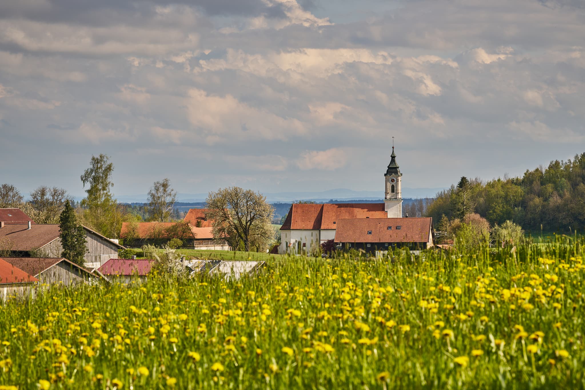 Frühlingshafte Ansicht von St. Wolfgang in Bad Griebsach bei Passau, Niederbayern. Eine malerische Kirche umgeben von saftigen Wiese.