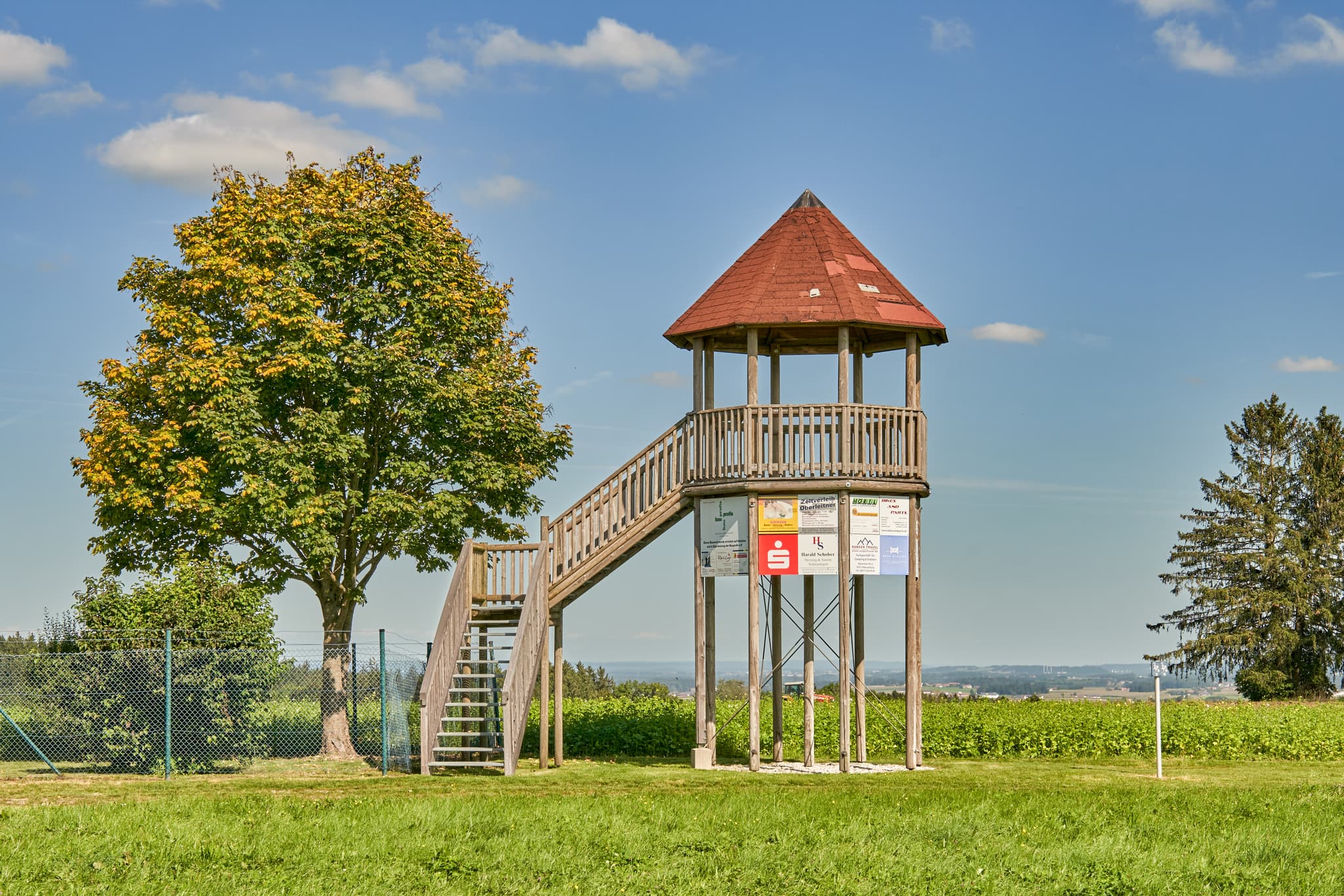 Aussichtsturm in Schnaitsee, Landkreis Traunstein, Oberbayern. Motiv: Turm auf Wiese mit Baum, blauer Himmel in der Region Chiemgau, Deutschland.