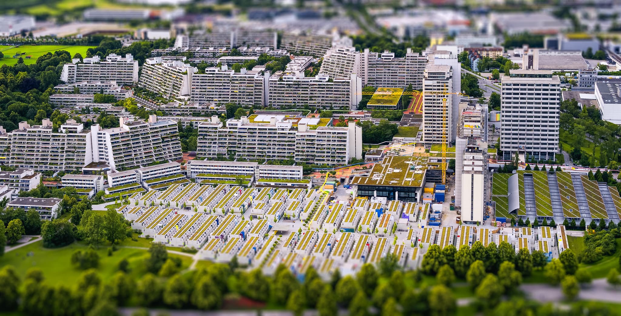 Tilt-Shift-Ansicht des Olympischen Dorfes in München. Das Bild zeigt Wohngebäude und grüne Bereiche in Münchner, Oberbayern, Deutschland.