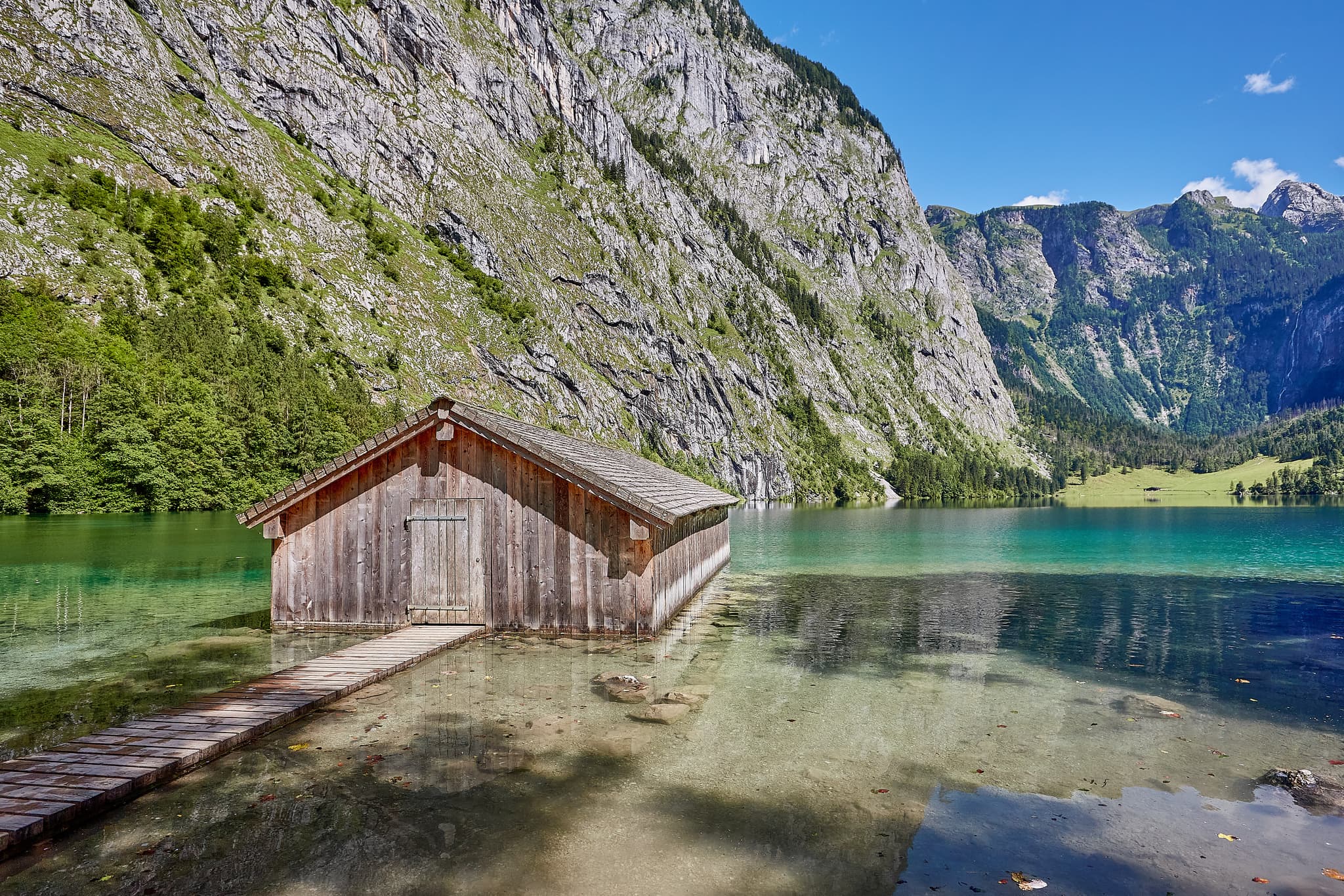 Malerisches Bootshaus am Obersee in Schönau, Berchtesgadener Land, Oberbayern, Deutschland. Klare Berglandschaft der Berchtesgadener Alpen umrahmt den See.