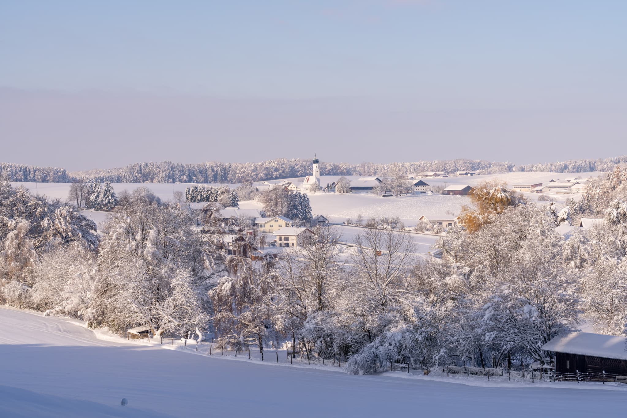 Verschneite Winterlandschaft in Eisenbuch, Erlbach, Landkreis Altötting, Oberbayern, Deutschland. Region Inn-Salzach mit Feldern, Bäumen und Häusern im Winter.
