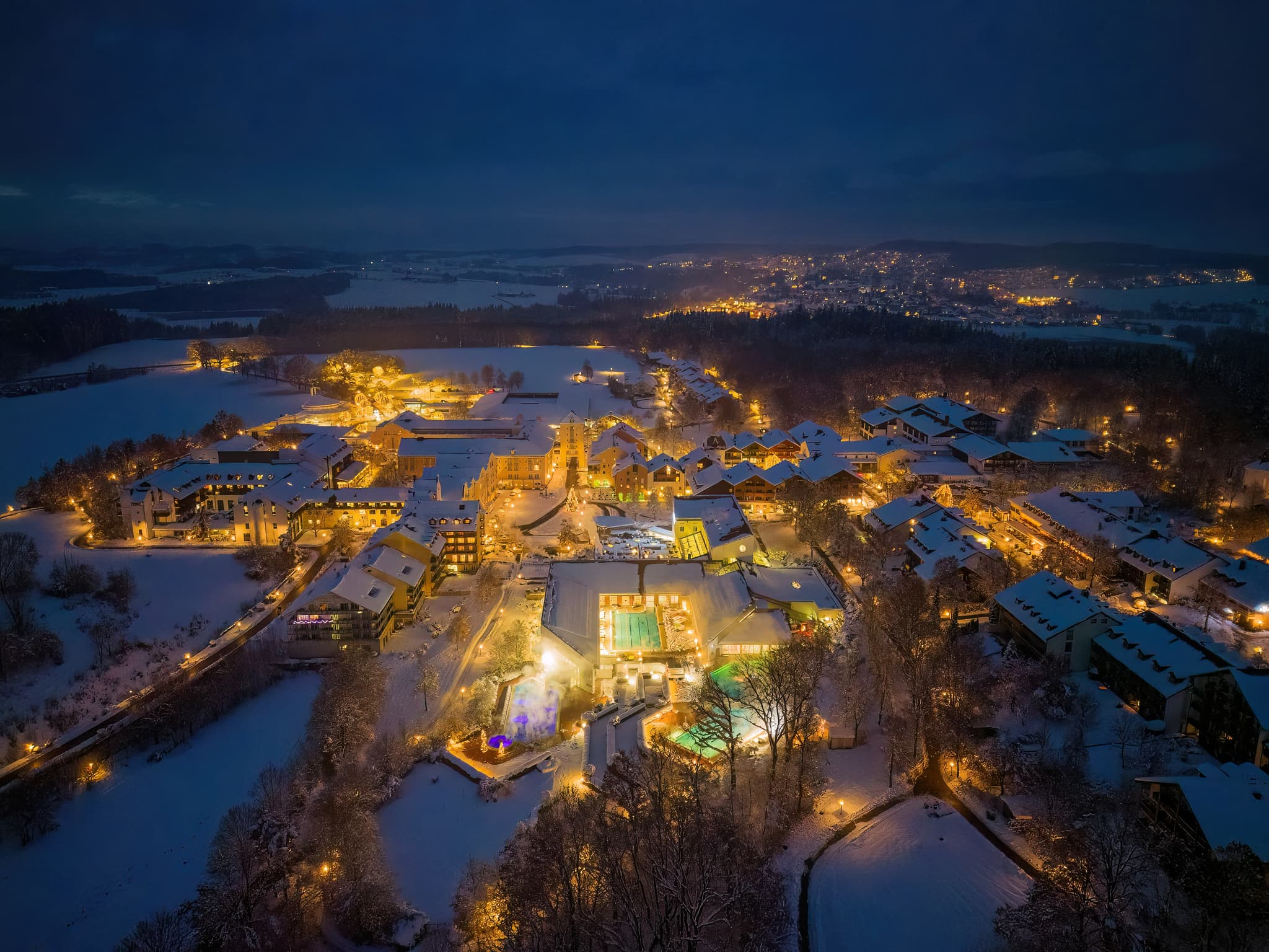 Nachtaufnahme der Therme Bad Griesbach im Winter. Das Bild zeigt die beleuchtete Thermenlandschaft und die umliegende, verschneite Bebauung, Bäderdreieck