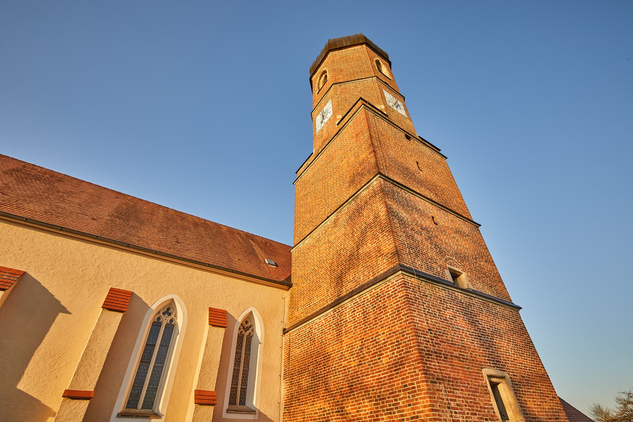 Kirchturm aus Ziegelmauerwerk mit angrenzendem Kirchenschiff unter blauem Himmel in Martinskirchen, Gemeinde Wurmannsquick, Rottal-Inn, Niederbayern, Holzland.