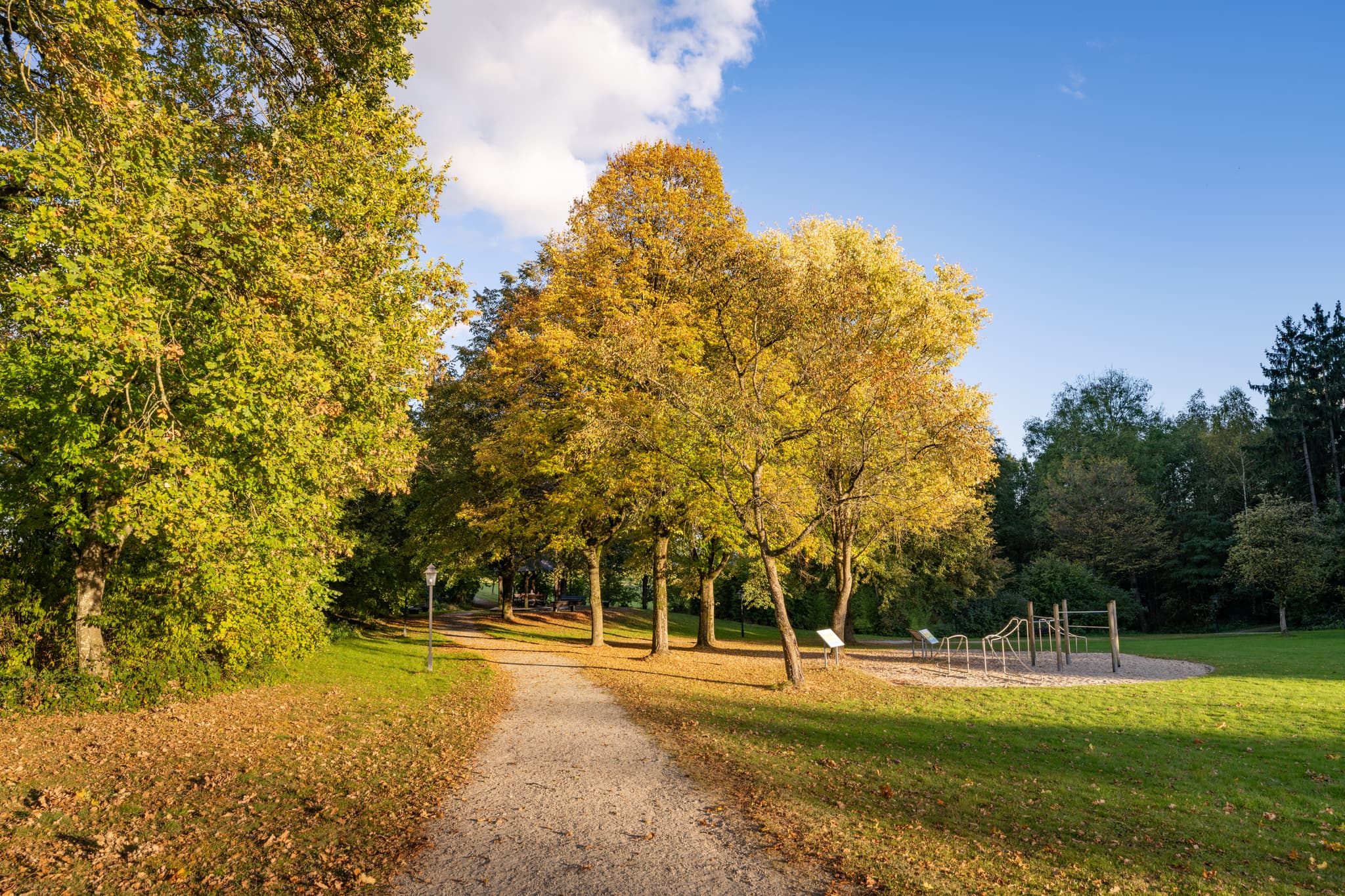 Herbstliche Impressionen aus dem Kurpark Bad Griesbach im Rottal, Landkreis Passau, Niederbayern, Deutschland. Einladende Wege und Bäume in warmen Farben.